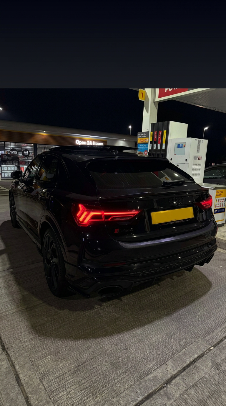 Black performance SUV at a petrol station at night